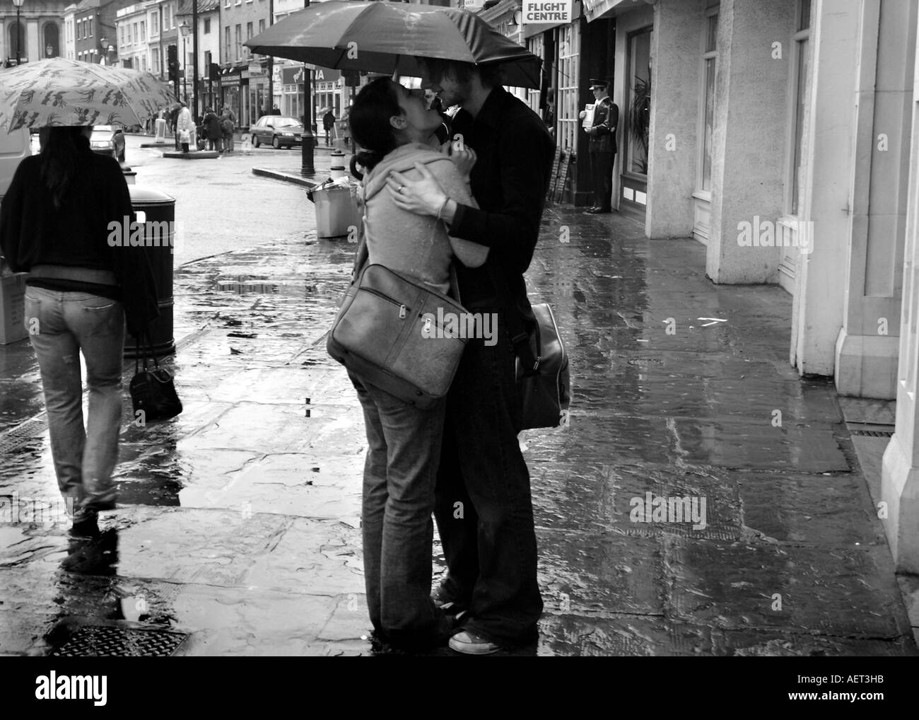 Due giovani amanti bacio sotto un ombrello a Greenwich Church Street al di fuori del Cutty Sark stazione della metropolitana di Londra, Regno Unito Foto Stock