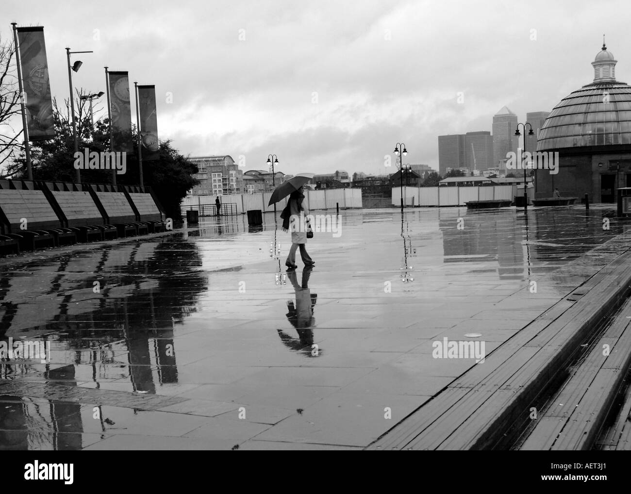Un pedone solitario in un giorno di pioggia sulla piattaforma al Cutty Sark Pier A LONDRA, REGNO UNITO Foto Stock