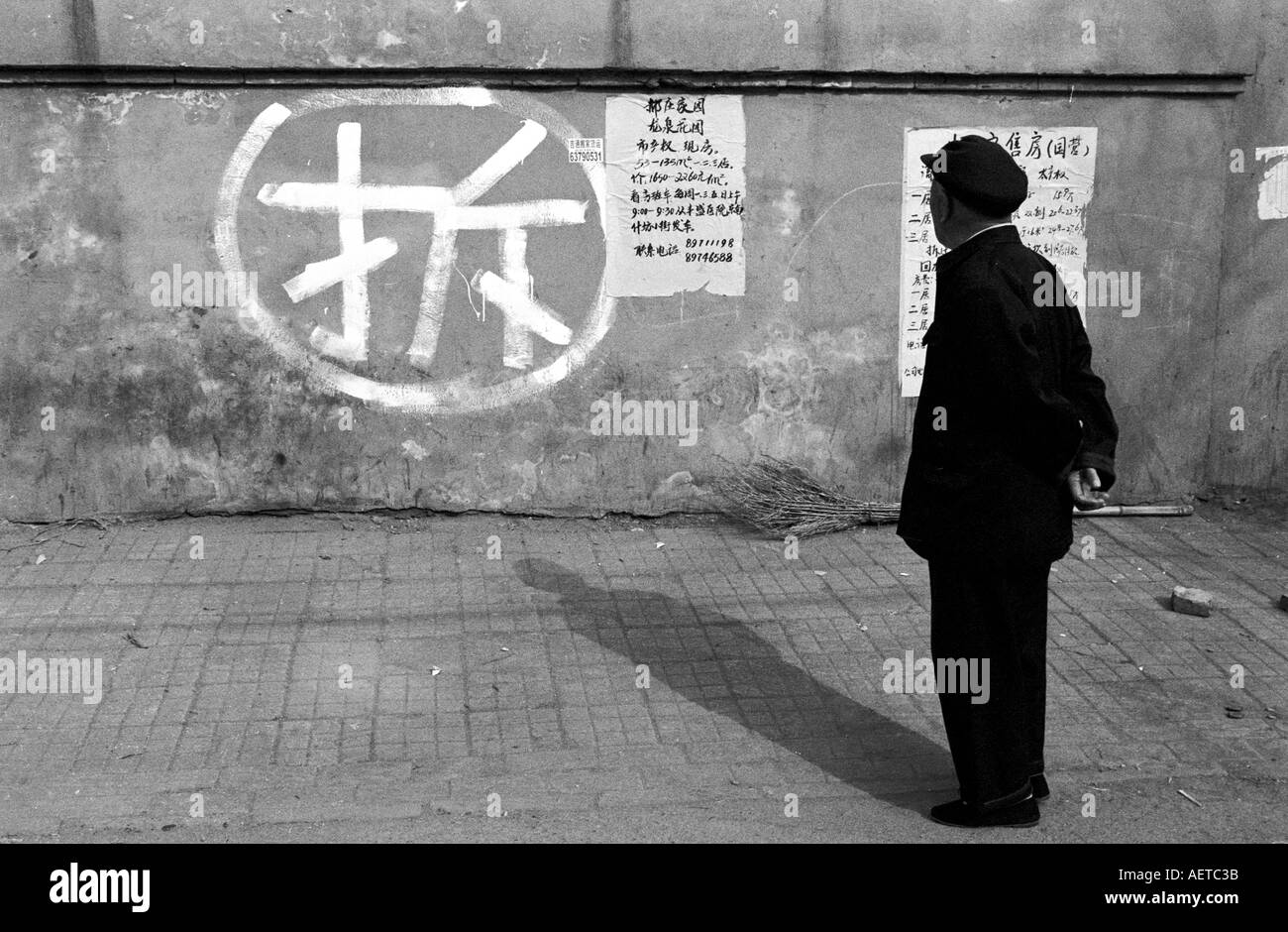 Un uomo legge il carattere cinese per i lavori di demolizione in un hutong di Pechino 2003 Cina Foto Stock