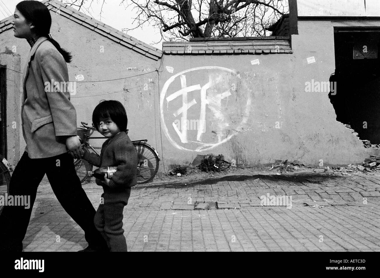 Una madre e figlia a piedi passato il carattere per i lavori di demolizione in un hutong di Pechino 2003 Cina Foto Stock