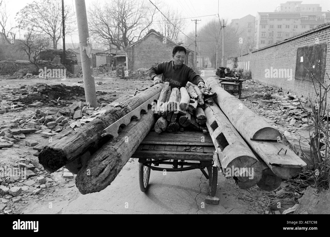 Un uomo Caricamento originali travi di legno per il riciclaggio da una casa demolita in un hutong di Pechino 2003 Cina Foto Stock