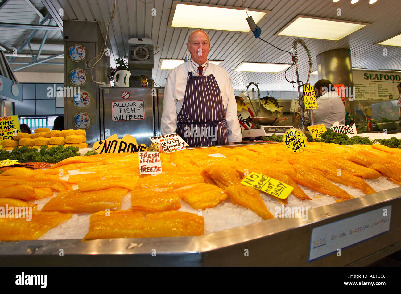 Commerciante di mercato presso la sua bancarella vendendo il pesce fresco England Regno Unito Foto Stock