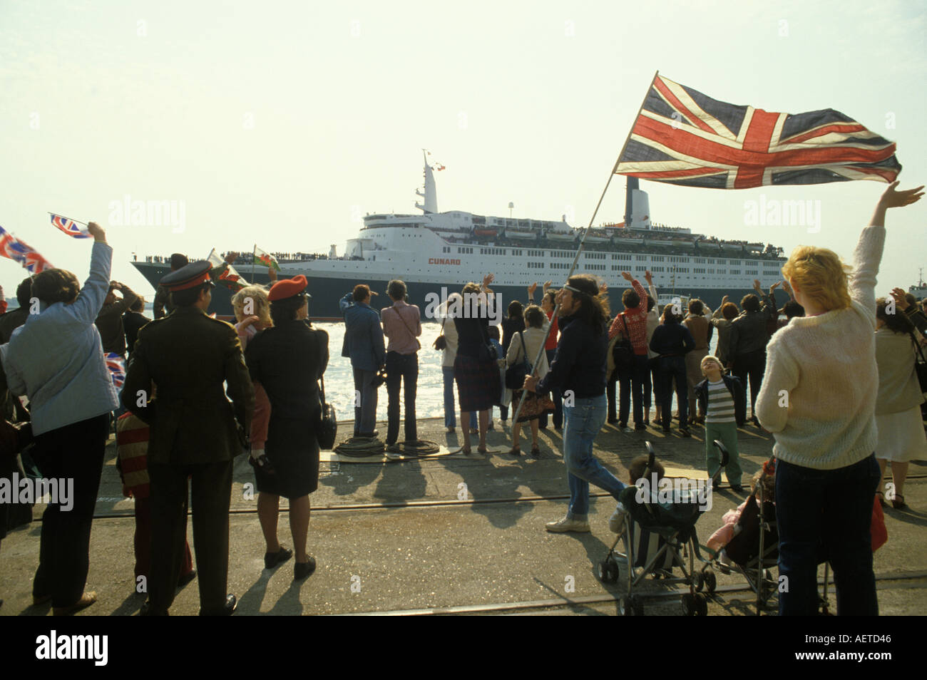 Nave Queen Elizabeth II. La QE2 parte per la guerra delle Falkland il 12 maggio 1982, Southampton Dock. Le famiglie sventolano una bandiera Union Jack e addio Regno Unito 1980S.. Foto Stock