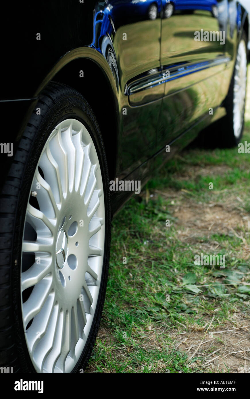 Il profilo laterale della Mercedes sport/berlina che mostra i dettagli di cerchi in lega e di erba si riflette in verniciatura Foto Stock