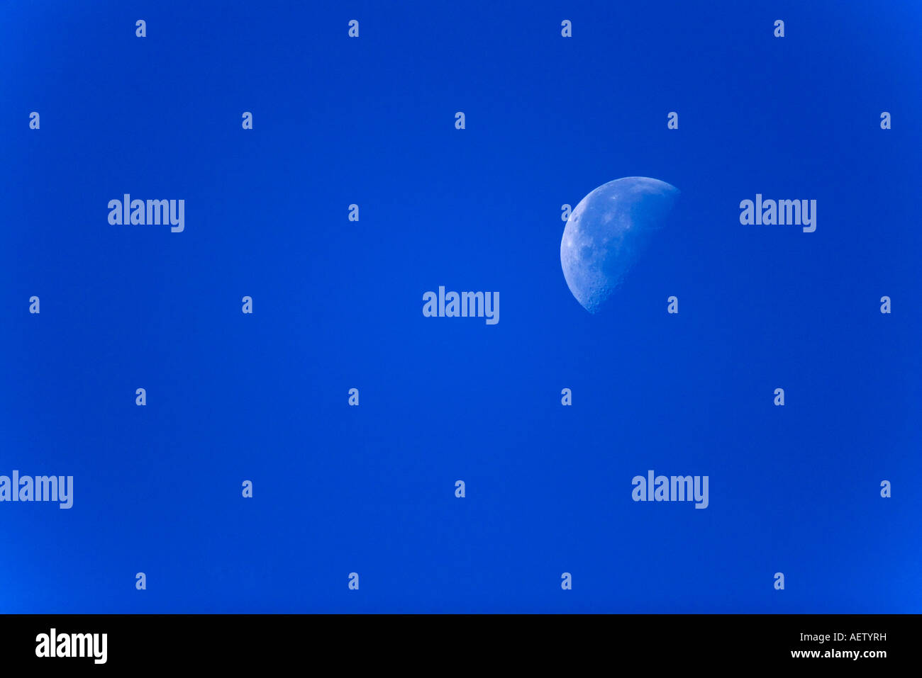 I tre quarti di luna set contro un cielo blu Foto Stock