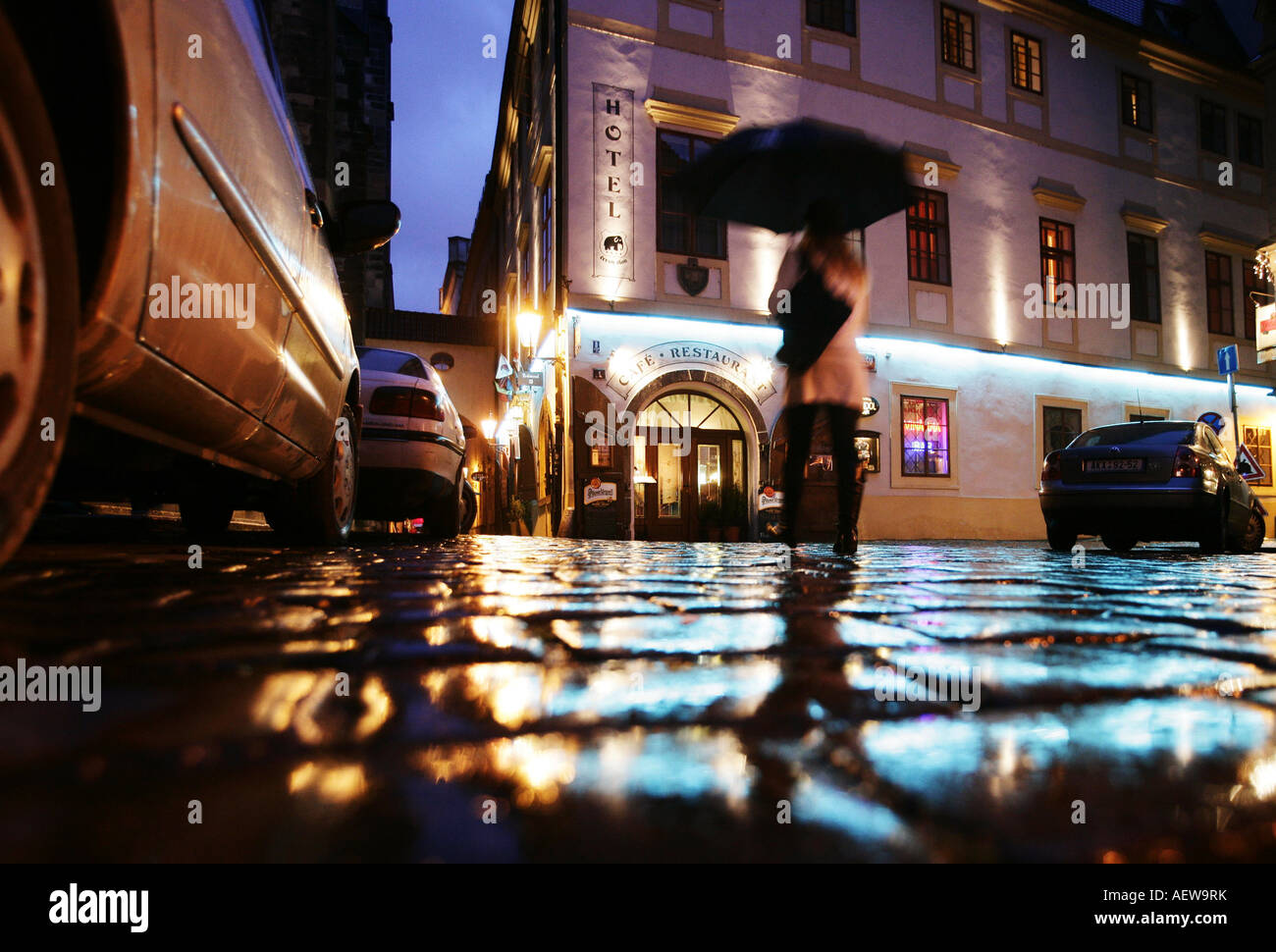 Reise Prag Tschechische Republik Frau mit Regenschirm geht auf nassem Kopfsteinpflaster, beleuchtetes Hotel,Innenstadt Prag Foto Stock