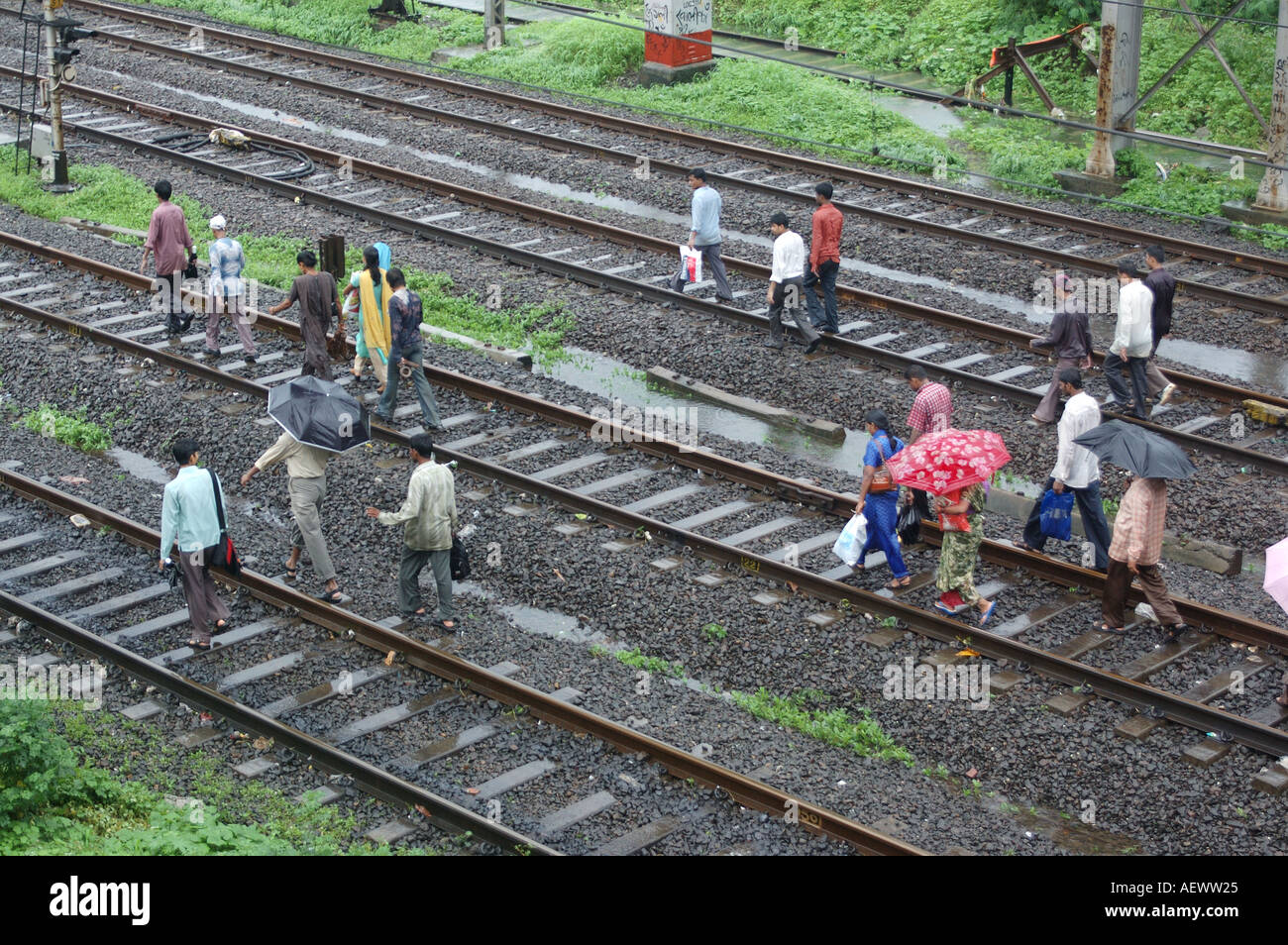 ANG71335 piogge monsoniche in Thane Maharashtra India mostrando persone che camminano sulla via ferroviaria treni n. Foto Stock