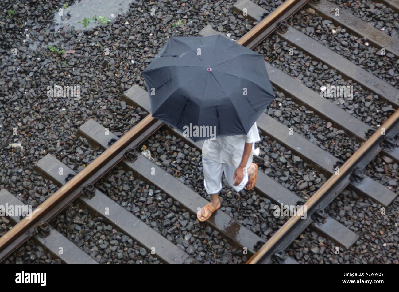 ANG71336 uomo a camminare sul binario ferroviario in un giorno di pioggia monsonica record mondiale la pioggia in Thane Maharashtra India Foto Stock