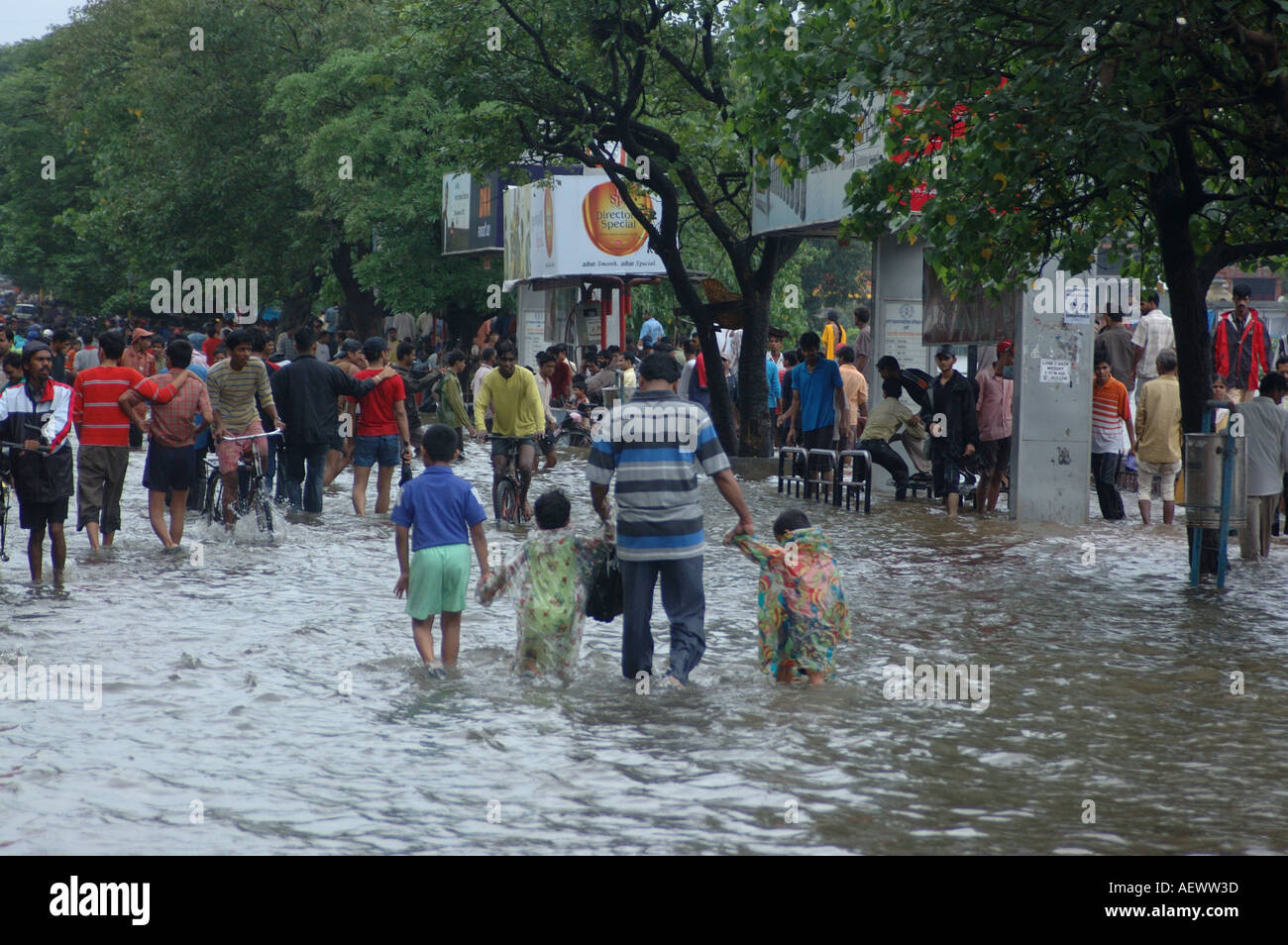 Famiglia a piedi in strada allagata dopo la pioggia monsonico a Bombay ora Mumbai India Foto Stock