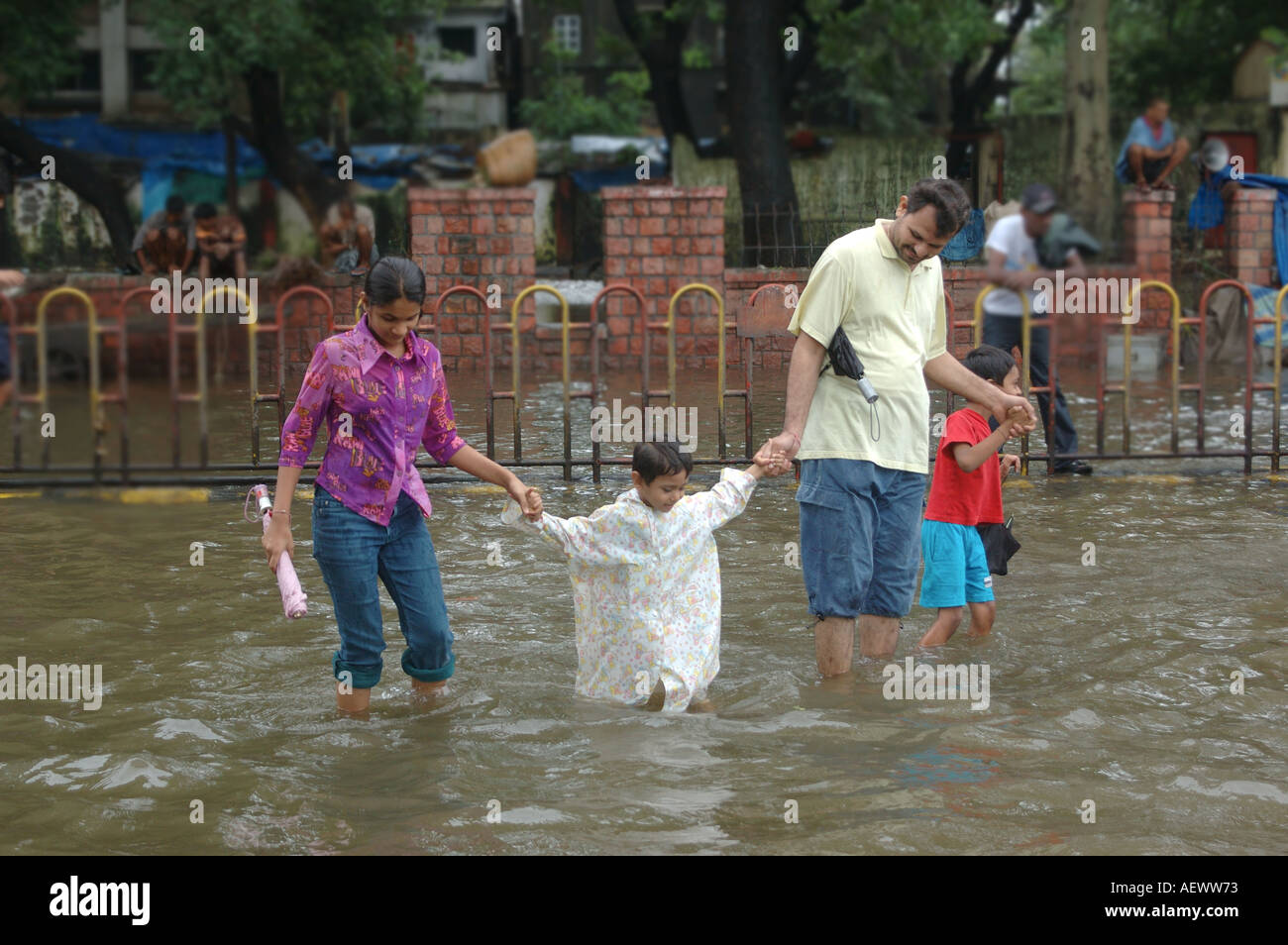 Famiglia a piedi in strada allagata dopo monsone pioggia a Bombay ora Mumbai India Asia Foto Stock