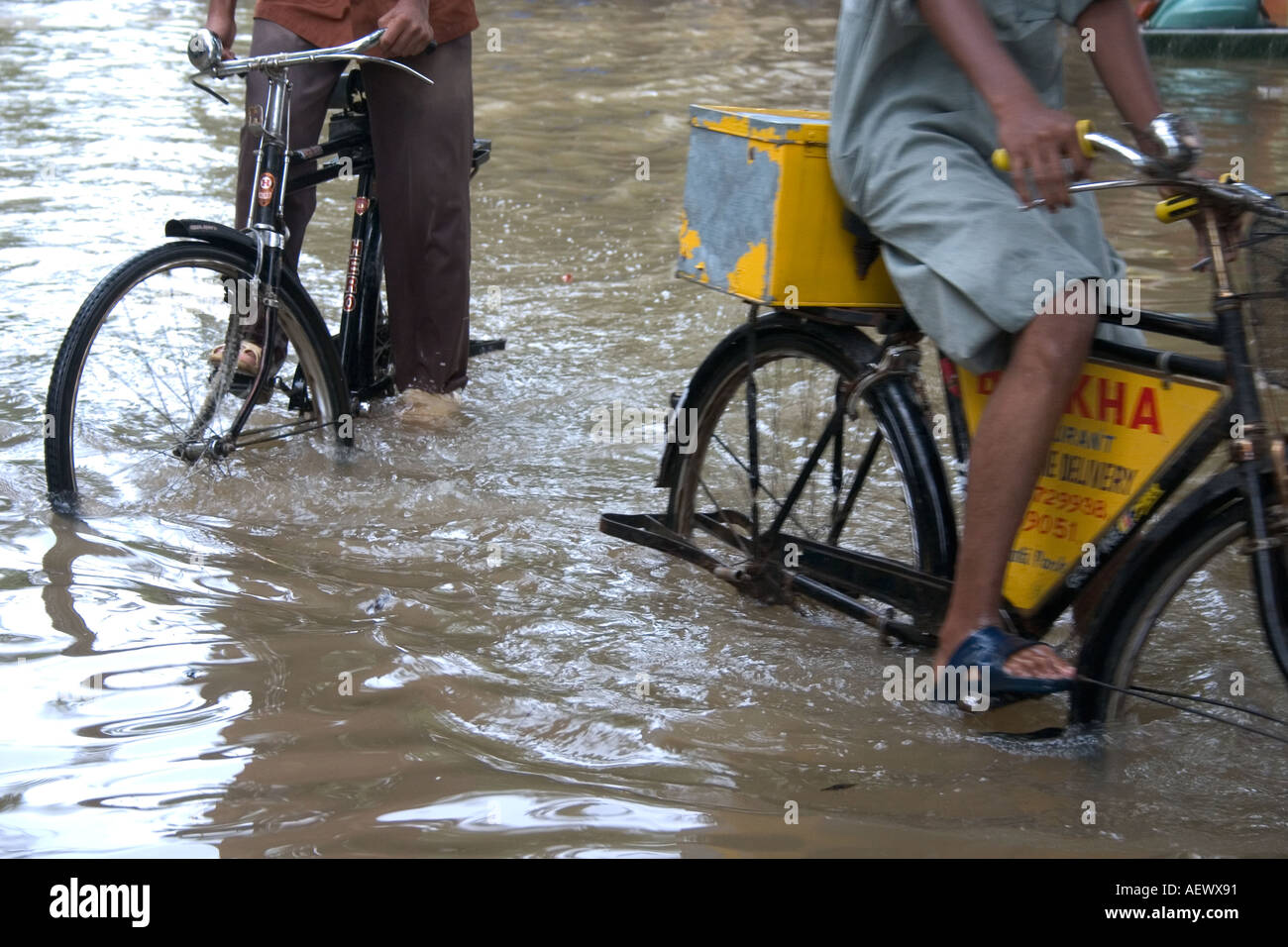 Uomini in bicicletta in strada allagata dopo la pioggia monsonico, Bombay, Mumbai, Maharashtra, India, Asia Foto Stock