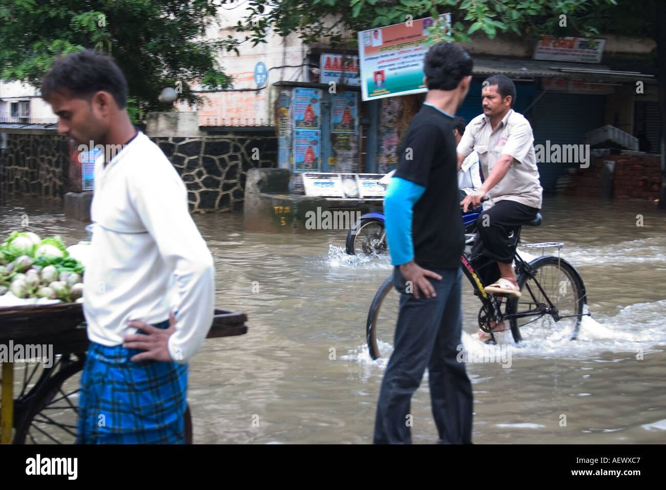 Uomini a piedi e in bicicletta in strada allagata dopo la pioggia monsonico, Bombay, Mumbai, Maharashtra, India, Asia Foto Stock