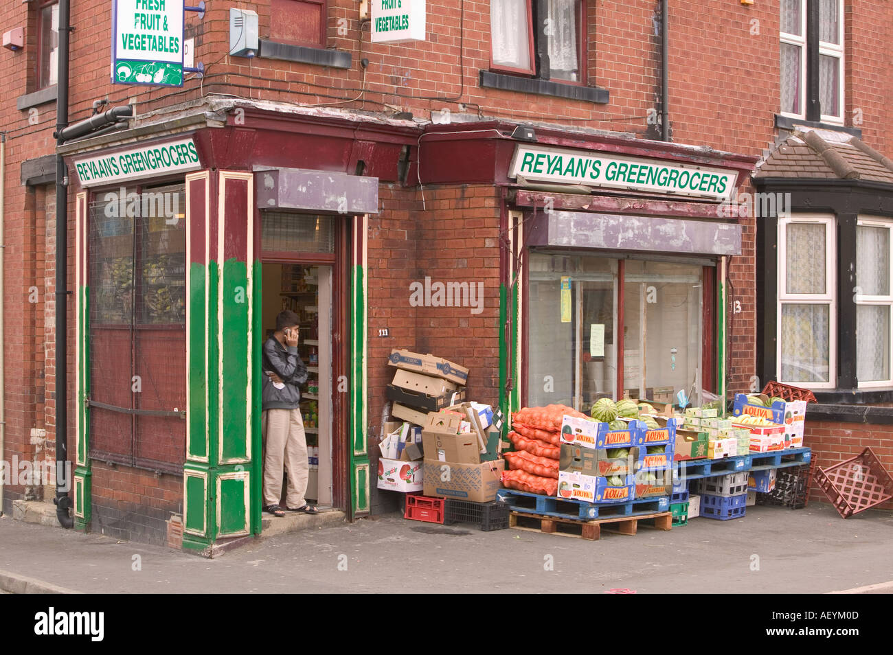 Uomo asiatico colloqui su un telefono cellulare in entrata di un piccolo negozio di Beeston Leeds Foto Stock