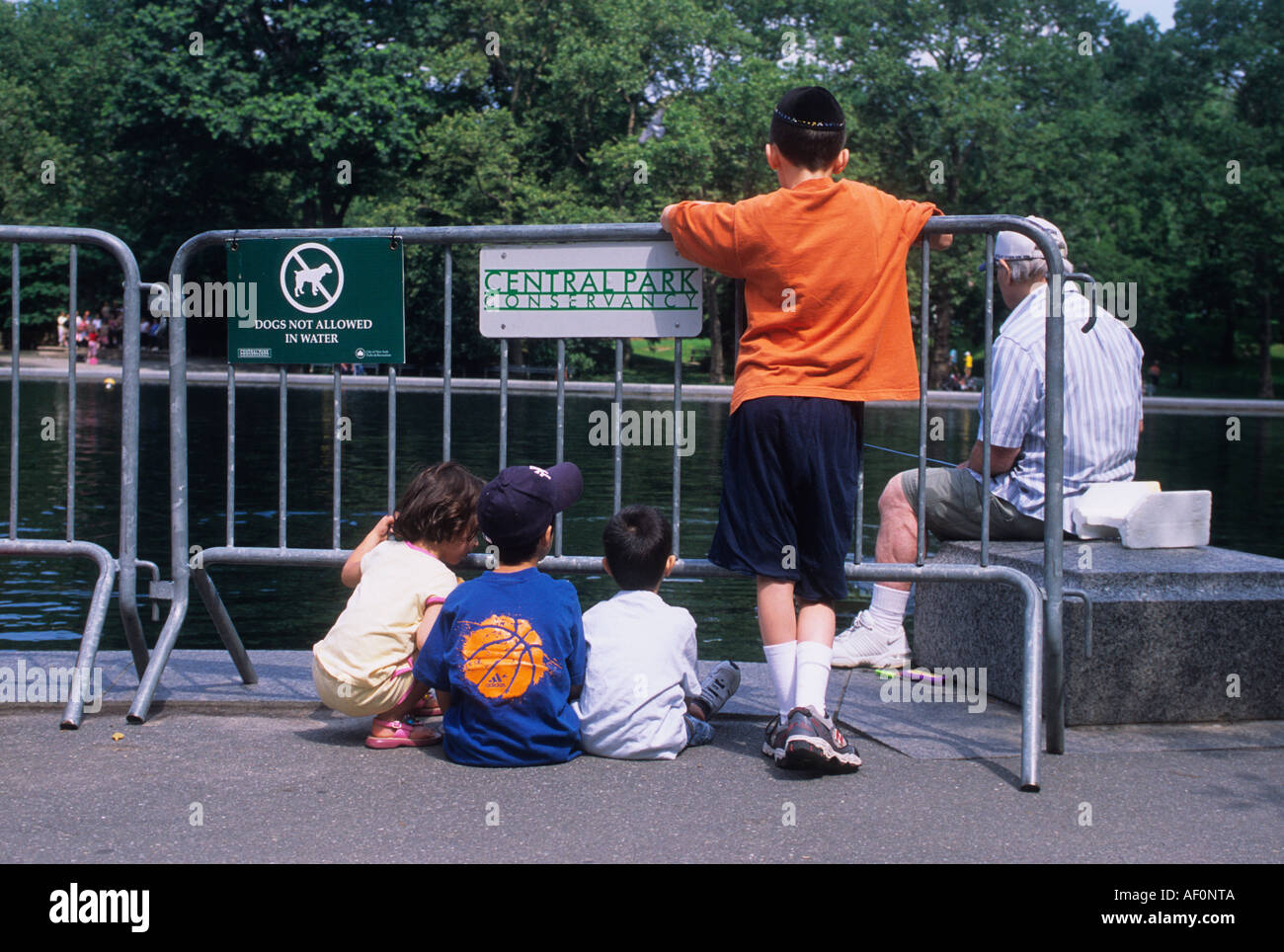 Stagno per imbarcazioni di Central Park. Conservatory Water, Boat Basin, New York Gruppo di persone nel parco. Cartello Central Park Conservancy. New York Stati Uniti Foto Stock