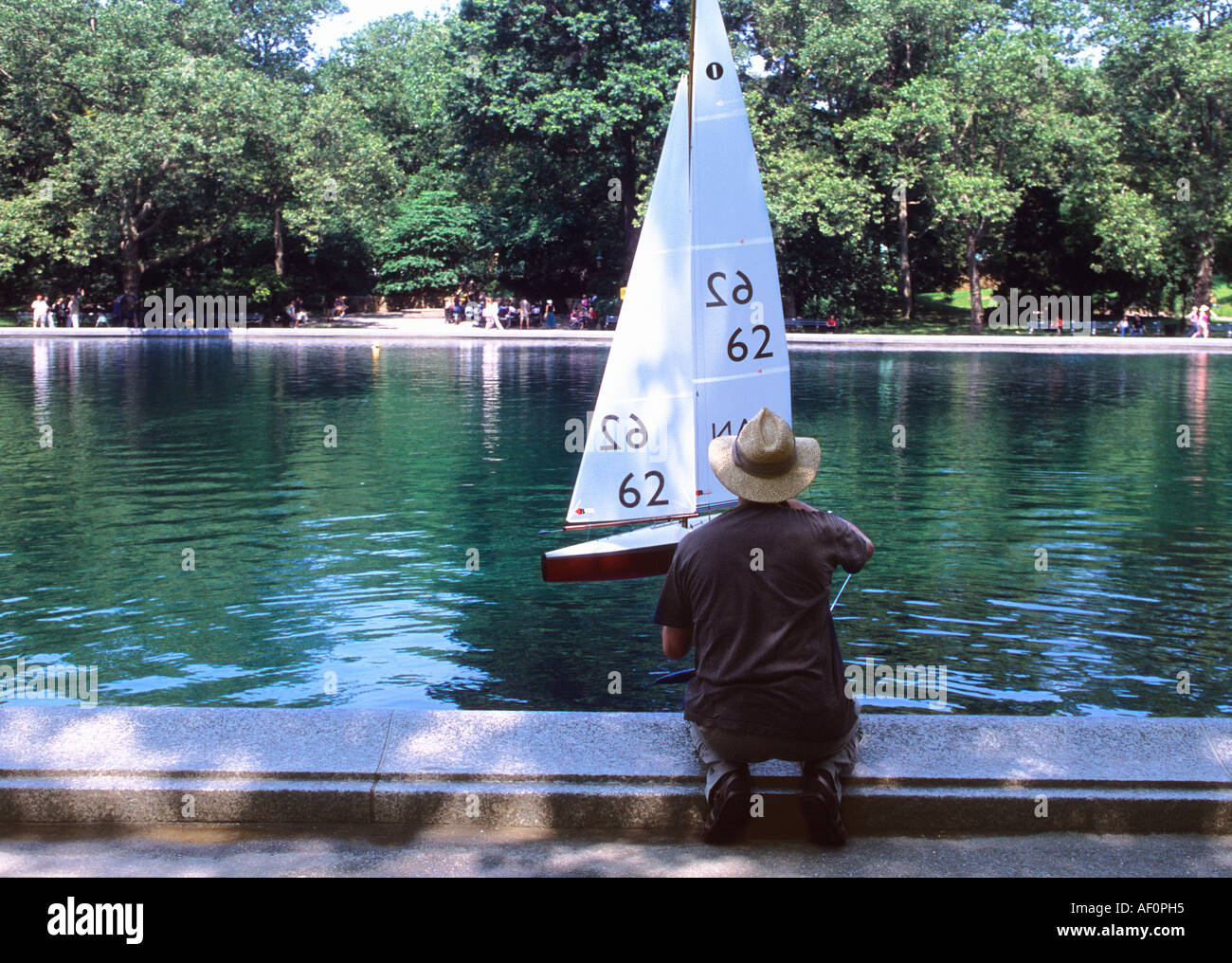 New York City, Central Park Boat Pond, il Conservatory Water. Uomo con un giocattolo modello a vela. Attività del Central Park intorno al bacino della barca. STATI UNITI Foto Stock