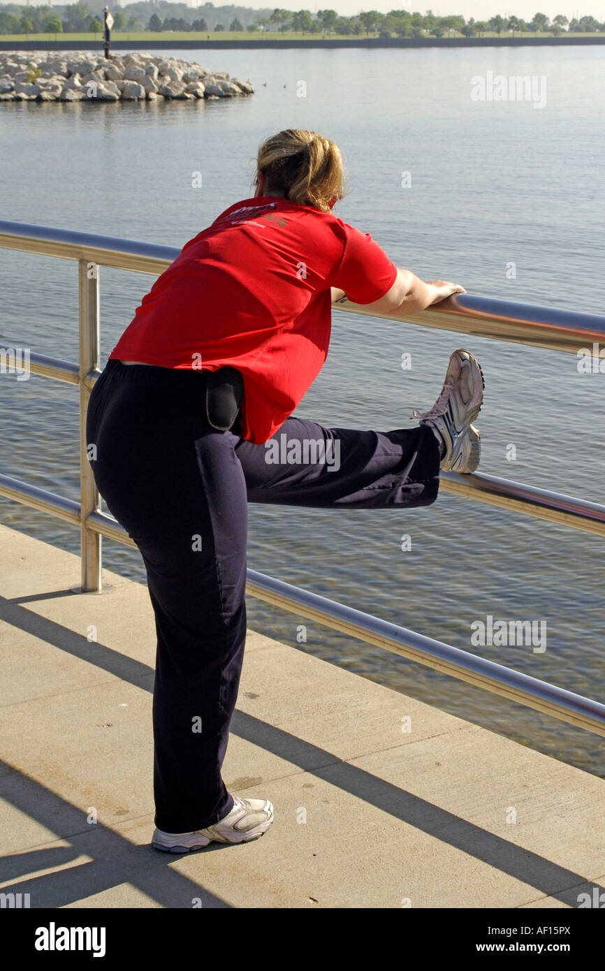 Donna di eseguire esercizi di stretching prima della sua corsa mattutina Foto Stock