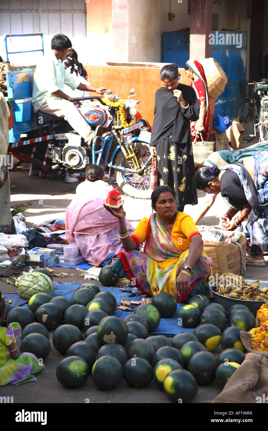 Venditore di frutta indiano che tiene in su pezzo di anguria con numerosi  cocomeri che giacciono sulla terra, Villaggio di pesca di Vanakbara, Isola  di Diu, Gujarat, India Foto stock - Alamy