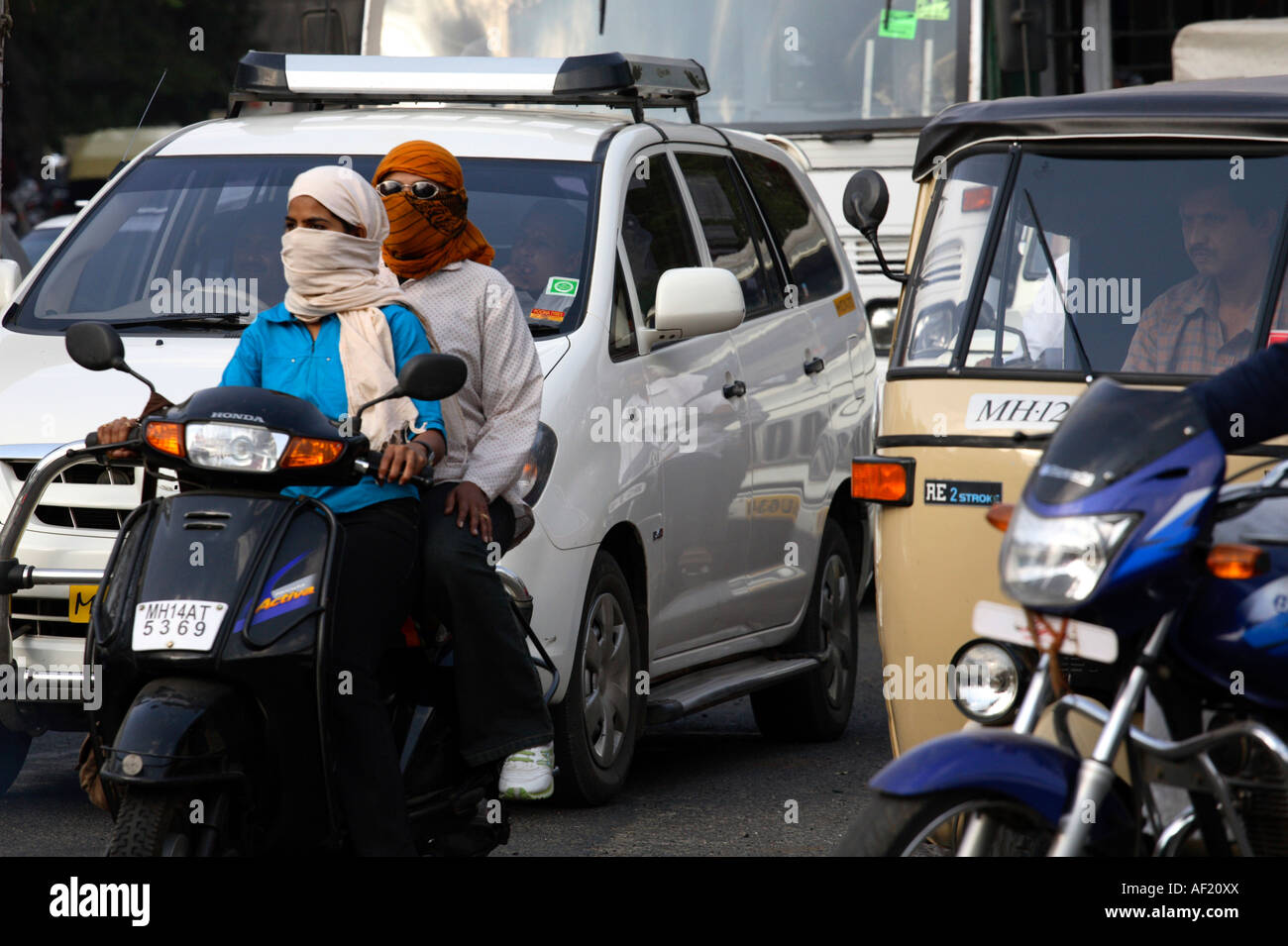Donne indiane che cavalcano scooter senza casco nel traffico trafficato, Pune, India Foto Stock