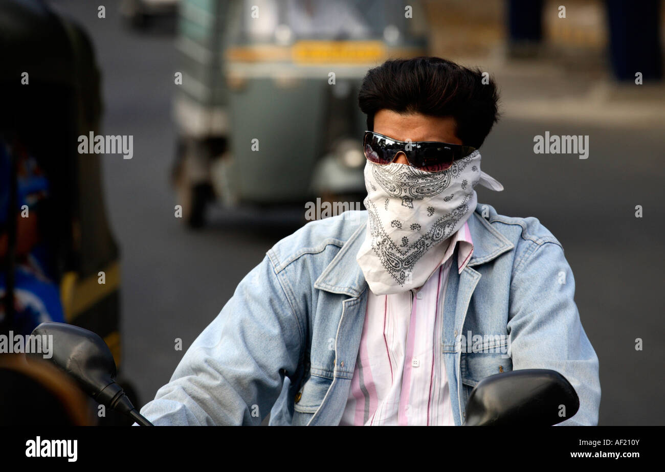 Primo piano di moto maschile indiano che indossa maschera facciale e senza casco nel traffico trafficato, Pune, India Foto Stock