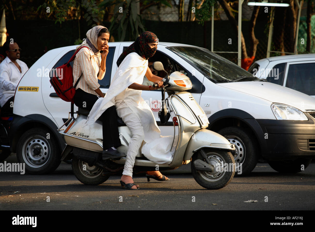 Giovane donna indiana che guida scooter senza casco indossare kameez salwaar nel traffico intenso, Pune, India Foto Stock