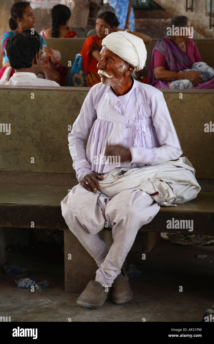 Indiano maschio da Rabari Tribe vestito in tradizionale kediyun, turbano bianco che aspetta a una bus-stand, Gujarat, India Foto Stock