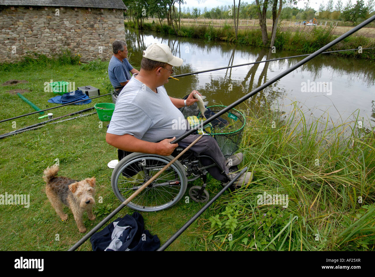 Disabilitato uomo helper e la pesca nel fiume Claise, Indre, Francia. Foto Stock