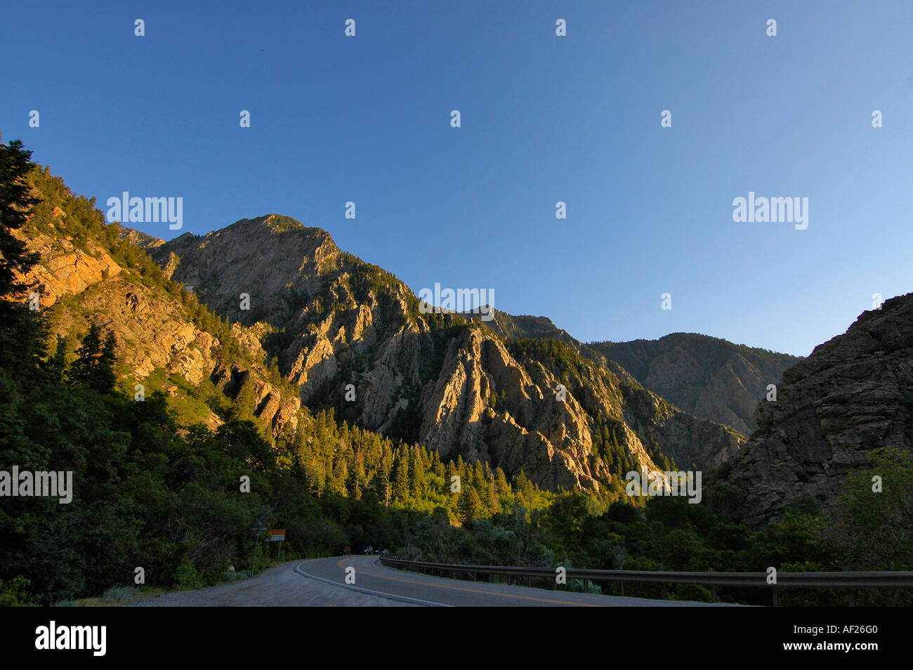 Aspre montagne rocciose in alto contrasto la luce del tramonto e una autostrada che scorre attraverso il primo piano Foto Stock