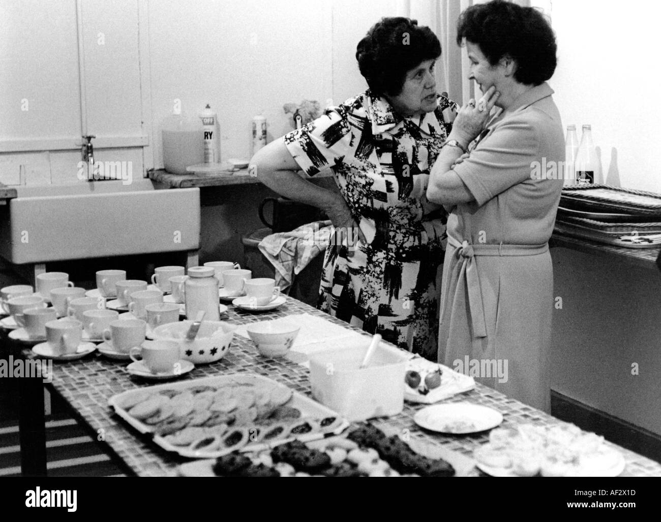 Due donne spettegolare mentre preparando il tè di pomeriggio evento locale. Foto Stock