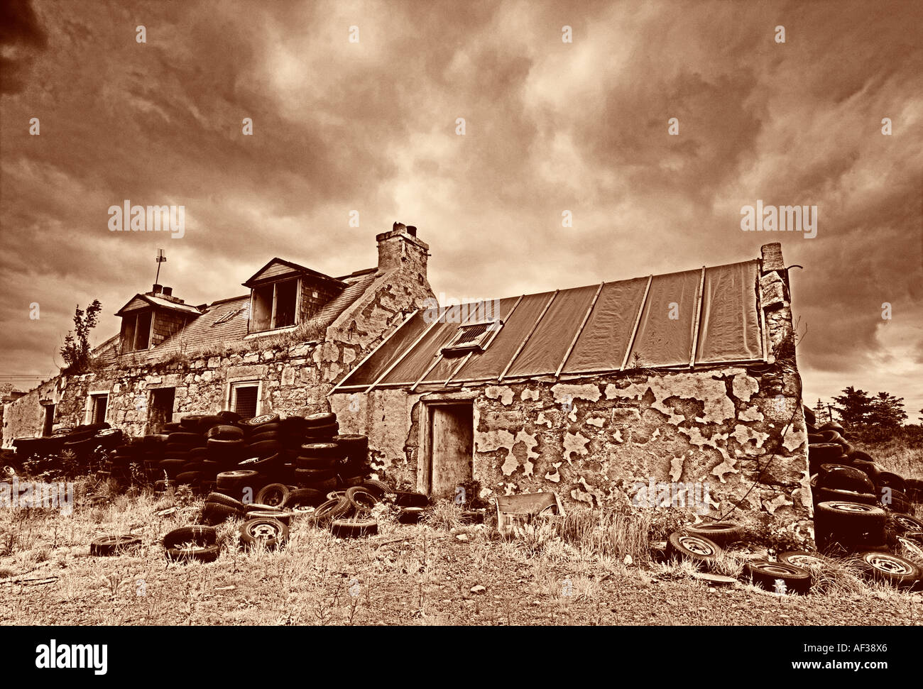 Un abstract seppia immagine oscurata da un cottage abbandonato casa colonica rurale con pneumatici di automobili in primo piano Foto Stock