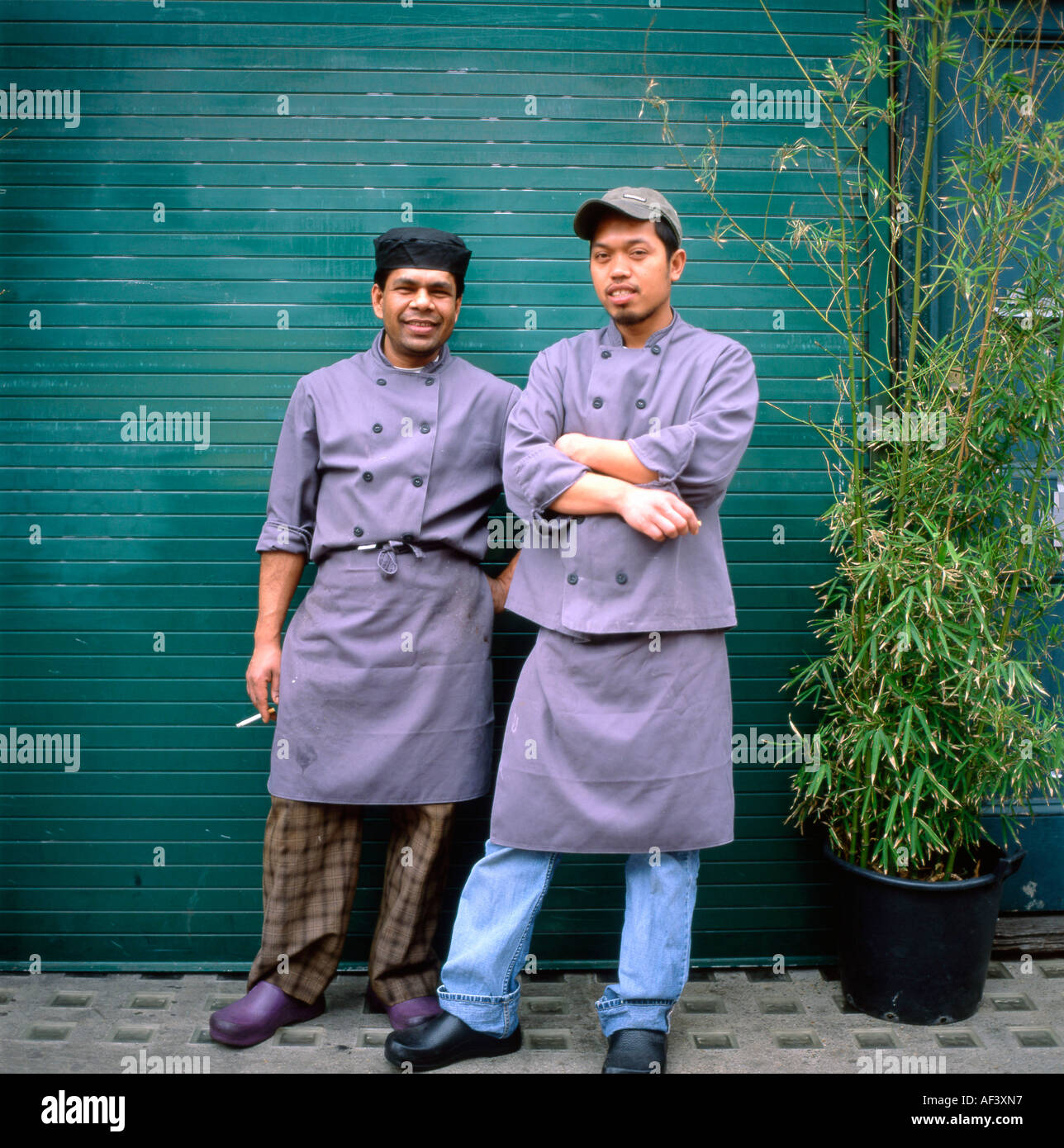 Immigrati lavoratori asiatici su una pausa di fumare al di fuori di un mercato di Borough ristorante Ponte di Londra Londra Inghilterra KATHY DEWITT Foto Stock