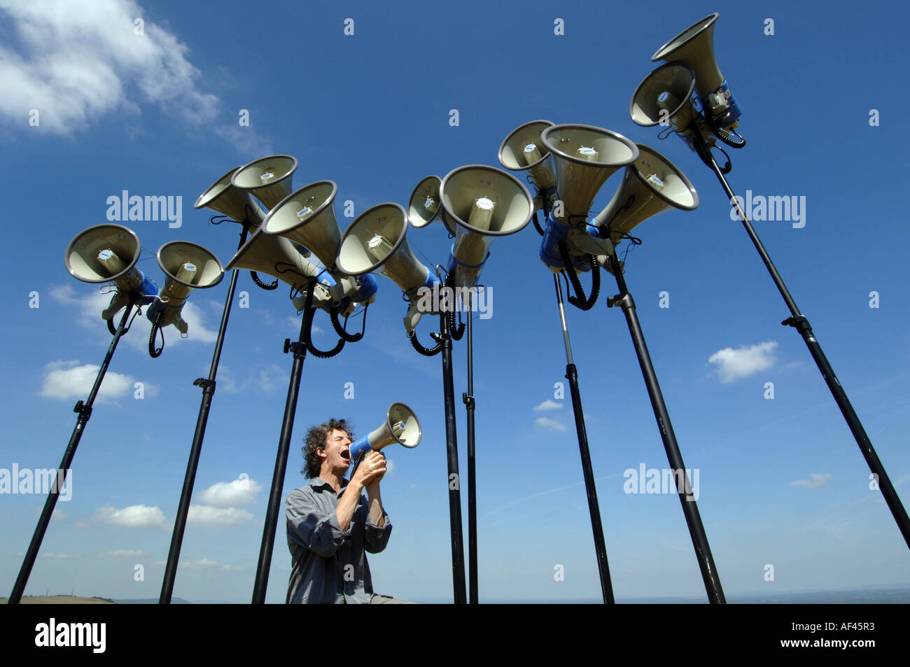 Compositore e direttore del coro gridare Orlando Gough con megafoni sui demoni Dyke, Sussex Foto Stock