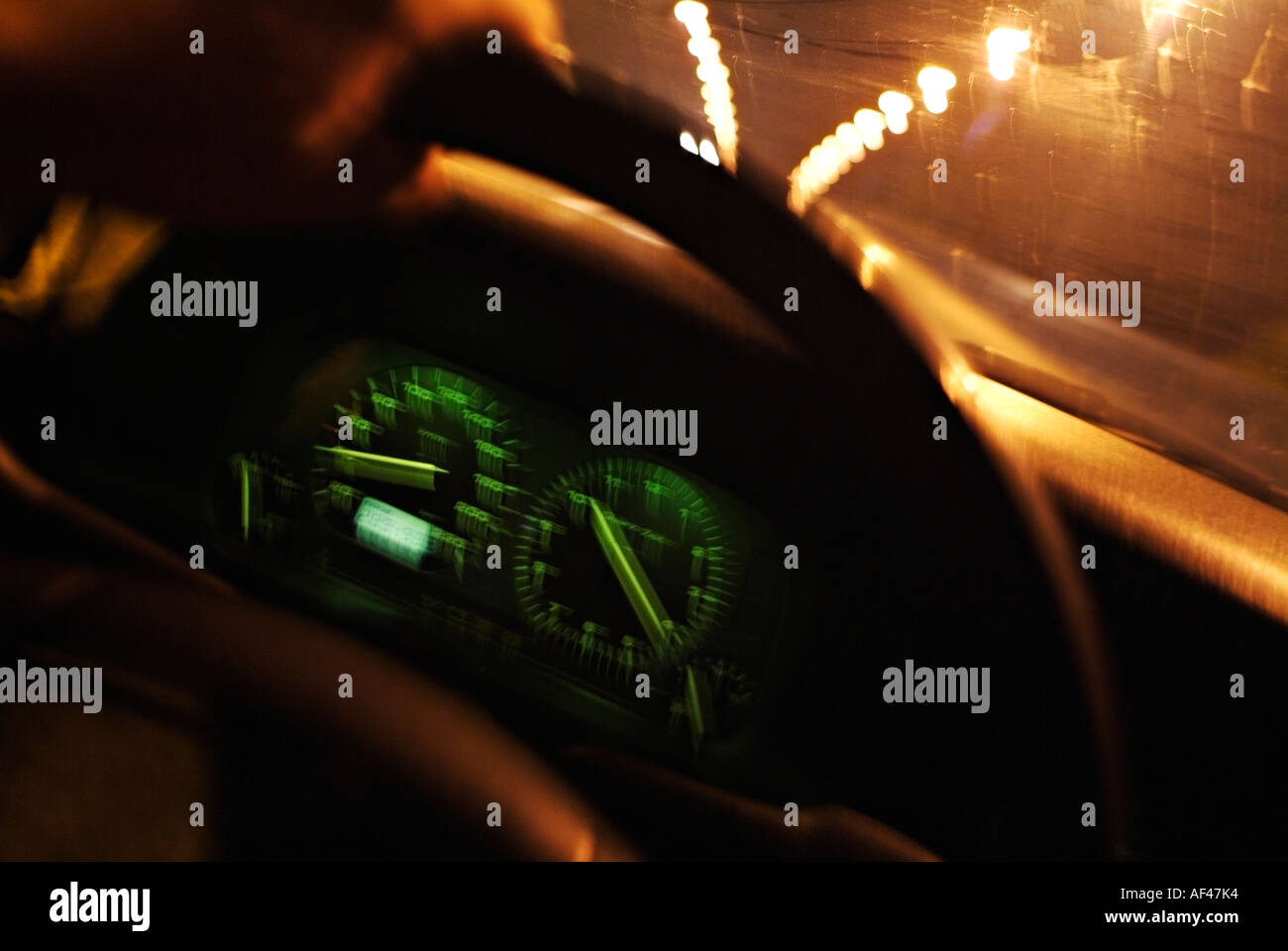 Driver vista dall'interno di un Guida auto di notte lungo una strada della città Foto Stock