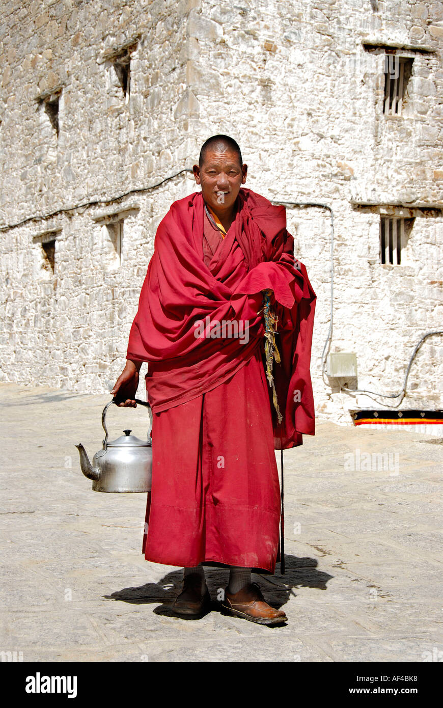 Monaco buddista vestito in abito rosso porta acqua pot Monastero di Drepung  Lhasa Tibet Cina Foto stock - Alamy