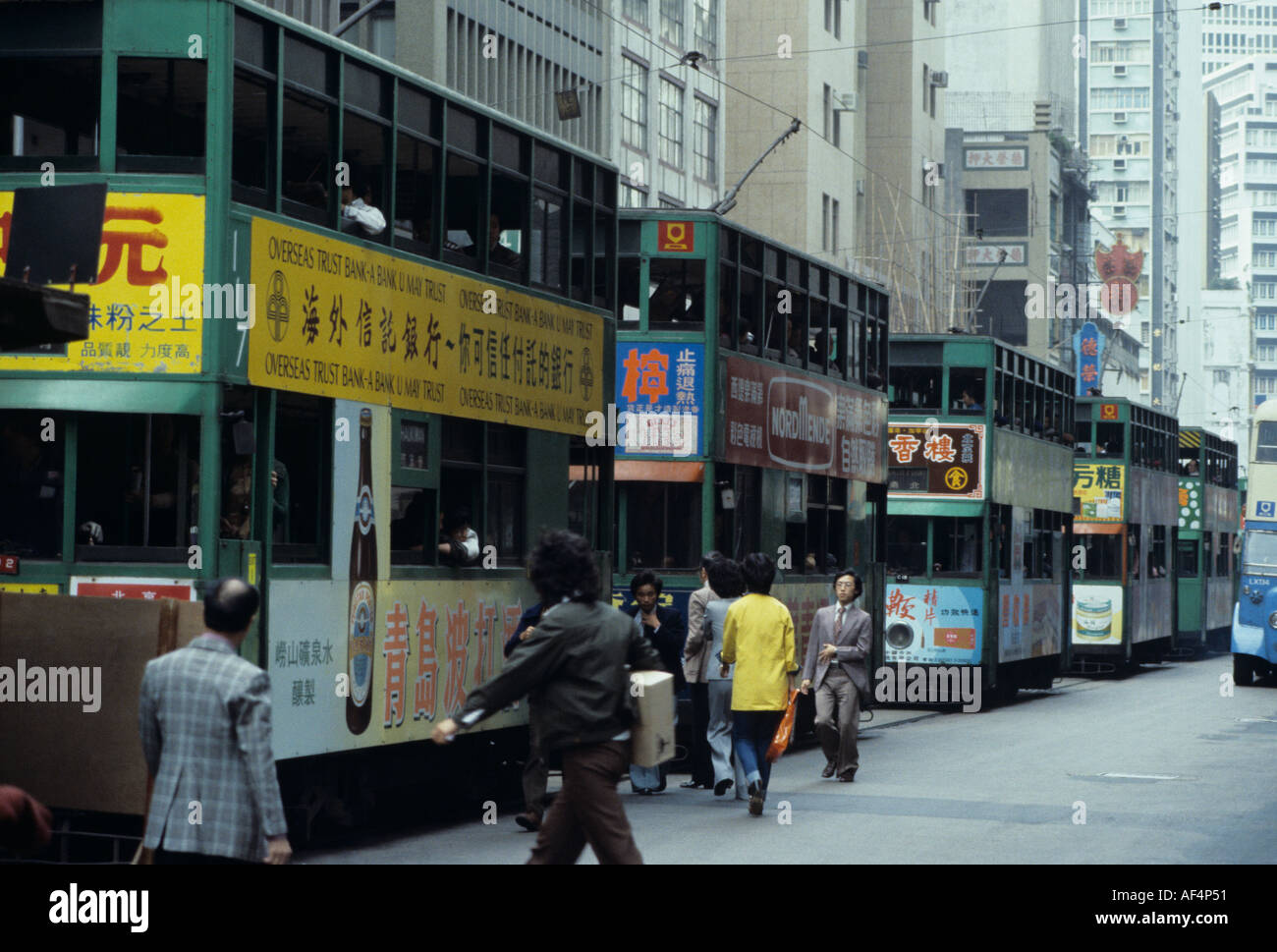 Una tipica linea di 5 vecchi tram verde cinese con inserzioni sui lati verso la fine degli anni settanta nel Distretto Centrale di Hong Kong Foto Stock