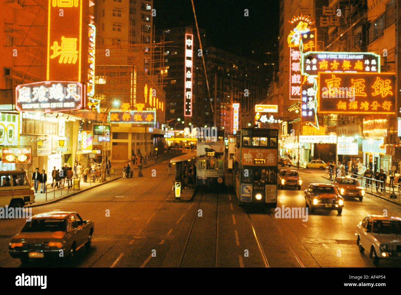 Vista di notte alla fine degli anni settanta di una strada larga in Causeway Bay con i tram vetture e luminose insegne al neon di Hong Kong Foto Stock