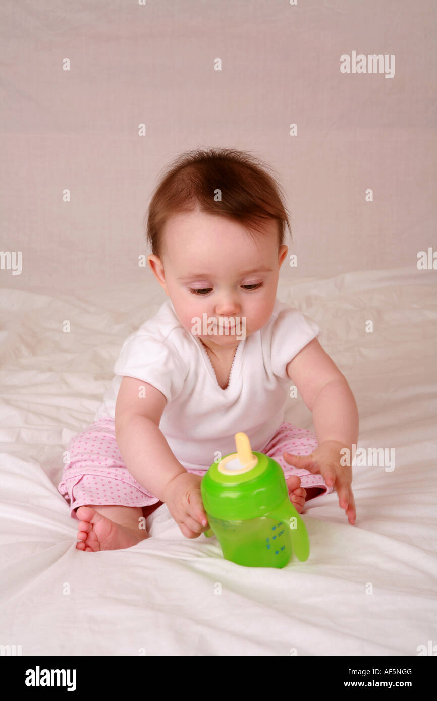 Giovane bambino neonato a 7 mesi raggiunge a prelevare un bimbo di colore  verde la coppa di alimentazione che mostra un motore avanzato di  coordinamento delle competenze Foto stock - Alamy