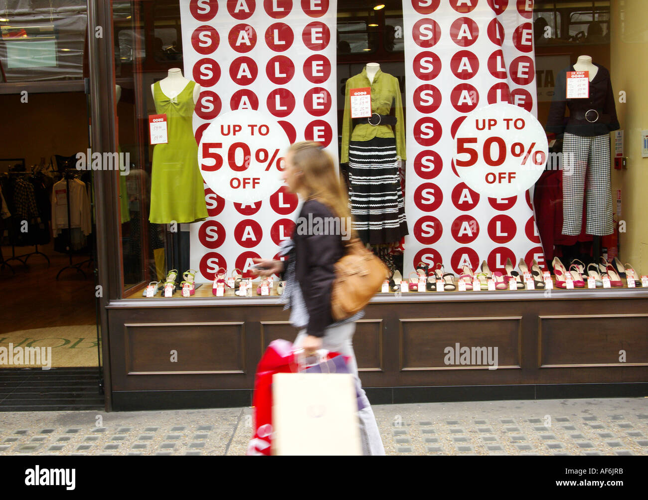 Una giovane donna è passata a piedi un negozio di vendita con le borse della spesa su Regent Street Londra Inghilterra REGNO UNITO Foto Stock