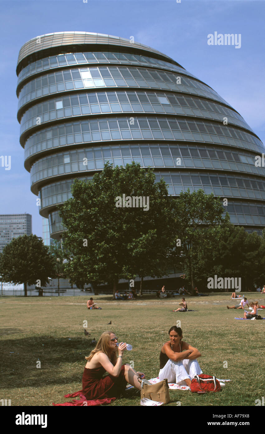 Regno Unito. In Inghilterra. Londra. Vista del nuovo municipio edificio e la gente seduta sul prato del parco circostante. Foto Stock