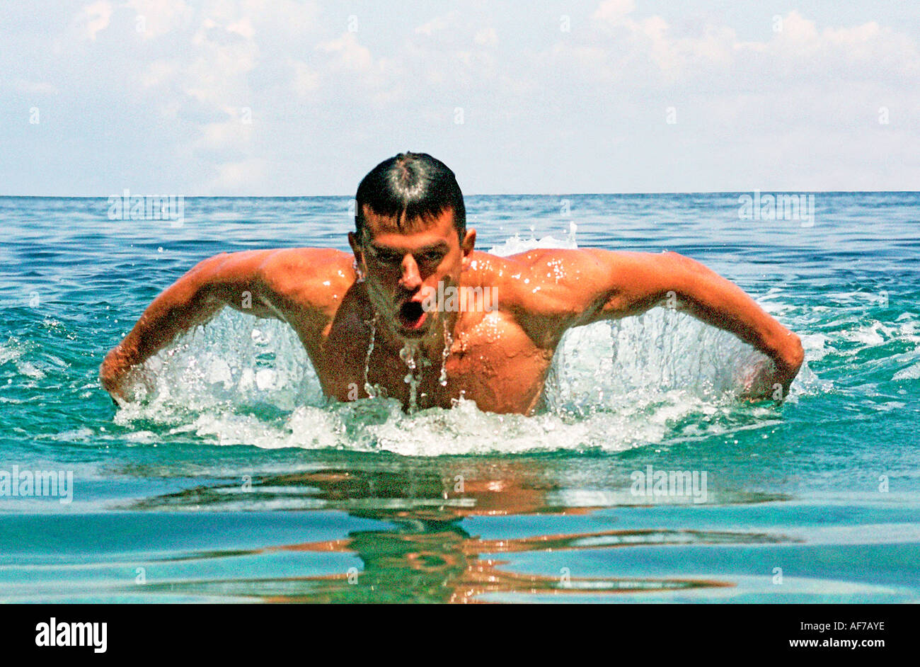 Uomo di nuoto corsa farfalla in calma il mare blu dell'acqua. Foto Stock