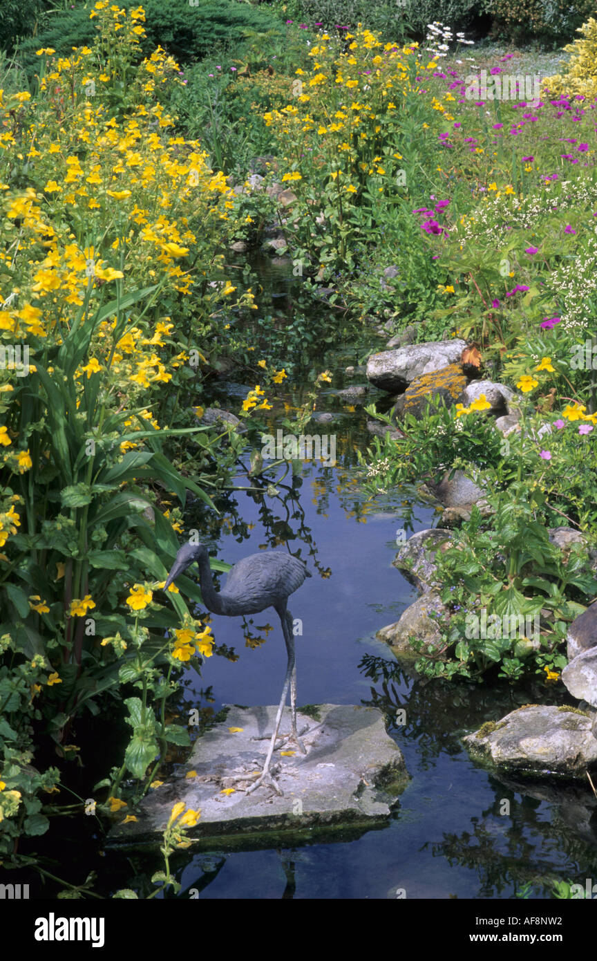 Margine di acqua piantagione, stream, Mimulus guttatus, fiore di scimmia, geranio, heron scultura deterent, percorso, il giardino delle farfalle, Foto Stock