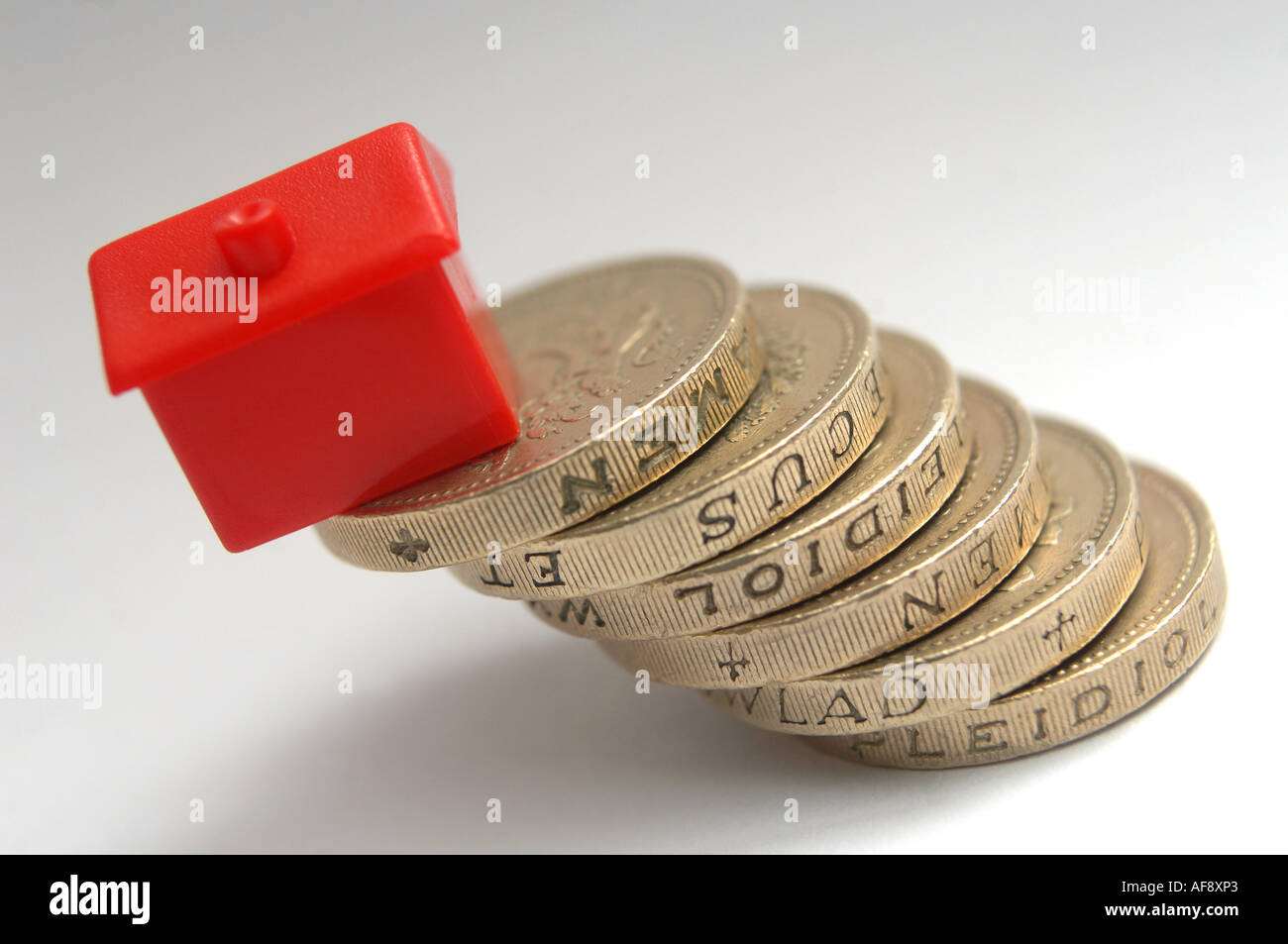 Una casa monolopy seduti sulla sommità di una pila o pile di monete per illustrare la variazione dei tassi di interesse e i prezzi delle abitazioni. Foto Stock