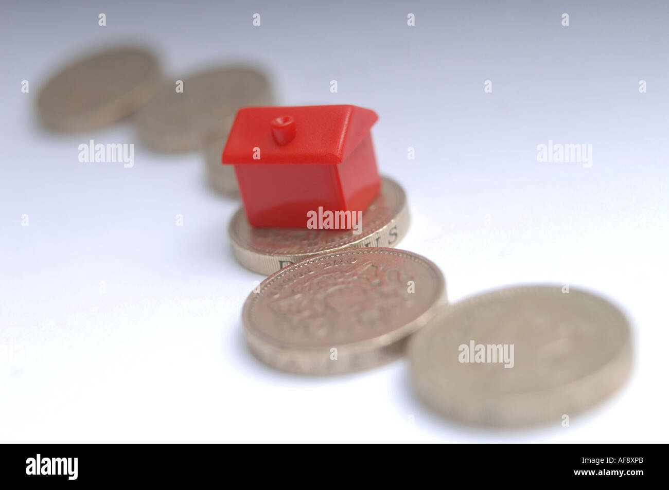 Una casa monolopy sulla sommità di monete per illustrare il prezzo della casa e i cambiamenti dei tassi di interesse Foto Stock