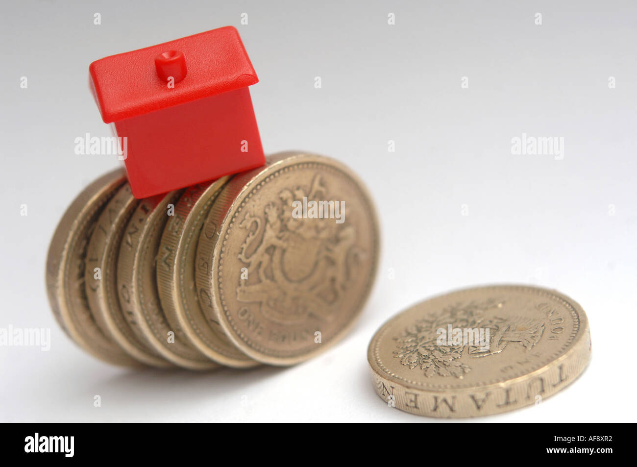 Una casa monolopy sulla sommità di monete per illustrare il prezzo della casa e i cambiamenti dei tassi di interesse Foto Stock