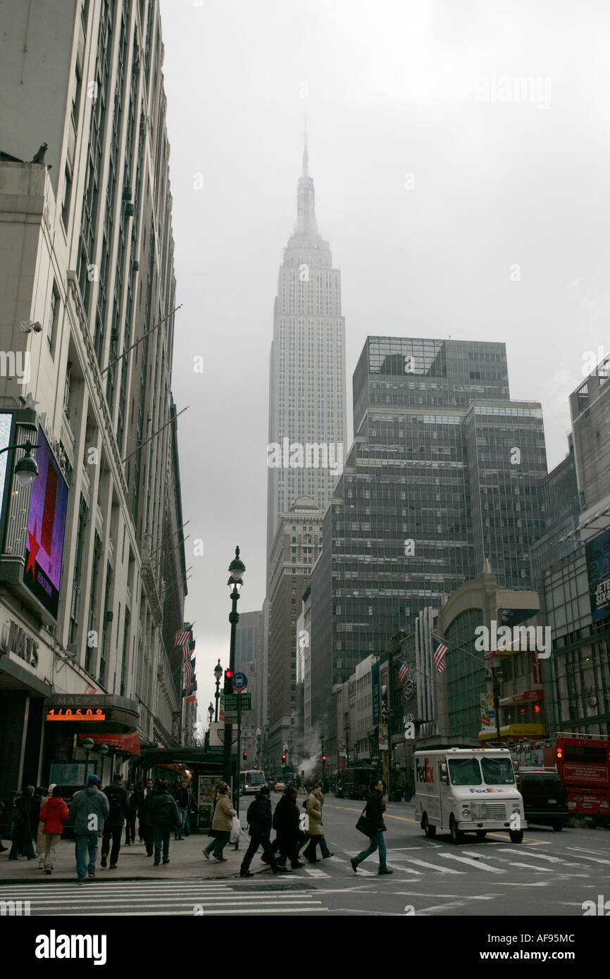 Empire State Building è avvolta nella nebbia come pedoni che attraversano crosswalk sulla 7th Ave e 34th street outside macys Foto Stock