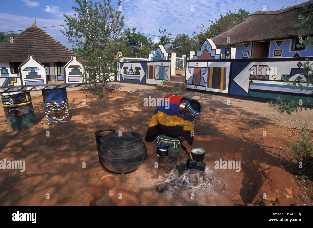 Sud Africa Mapoch Ndebele Village vicino a Pretoria donna case di cottura con tradizionali dipinti murali in background. Foto Stock