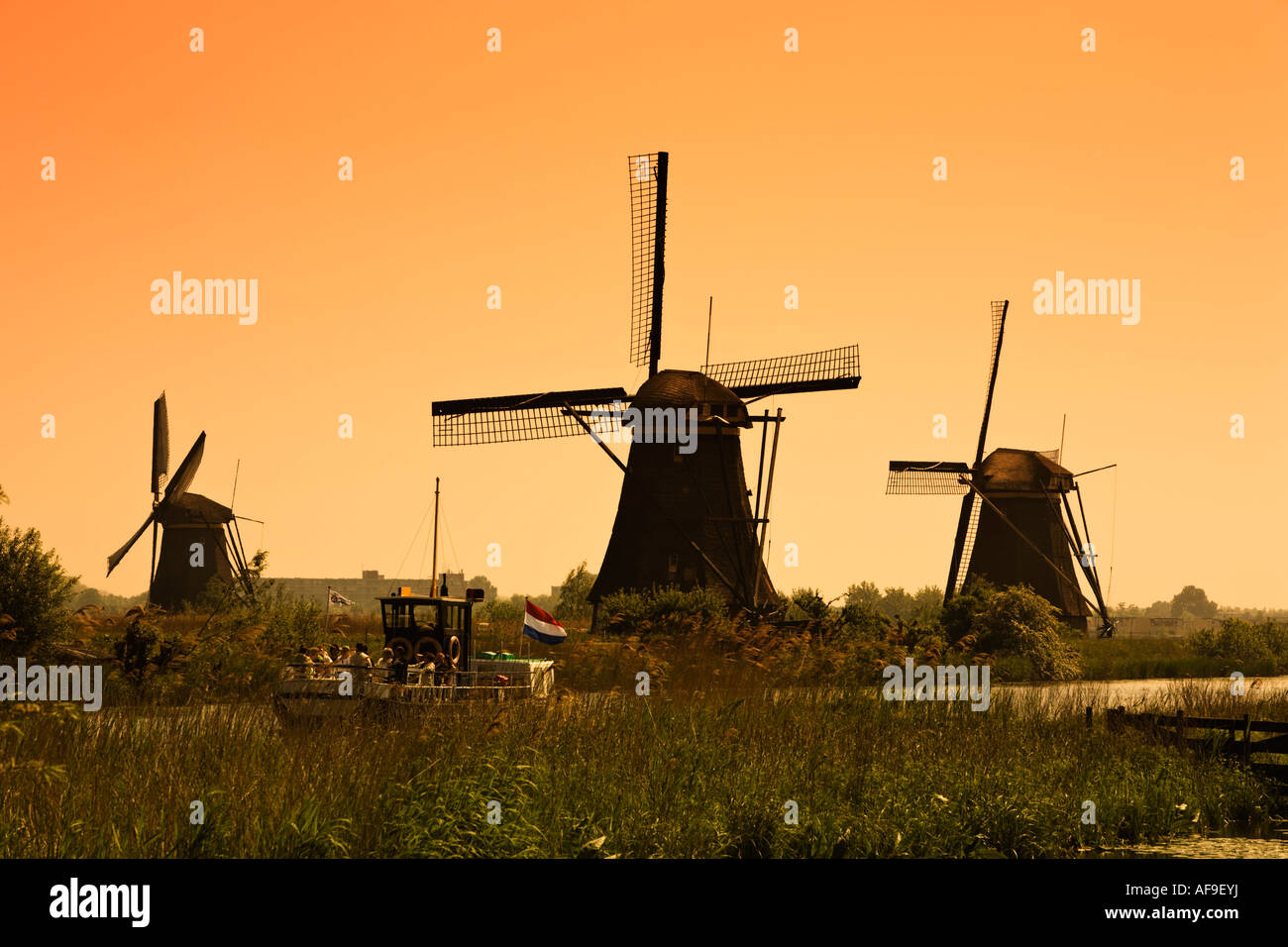 Turisti in un giro turistico in battello da crociera al tramonto la visualizzazione dei mulini a vento a Kinderdijk, Olanda - un sito Patrimonio Mondiale dell'UNESCO Foto Stock