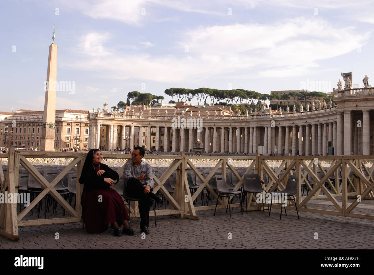 Una suora ed un laico in chat in Piazza San Pietro con l'Obelisco dal circo di Nerone in background. Foto Stock