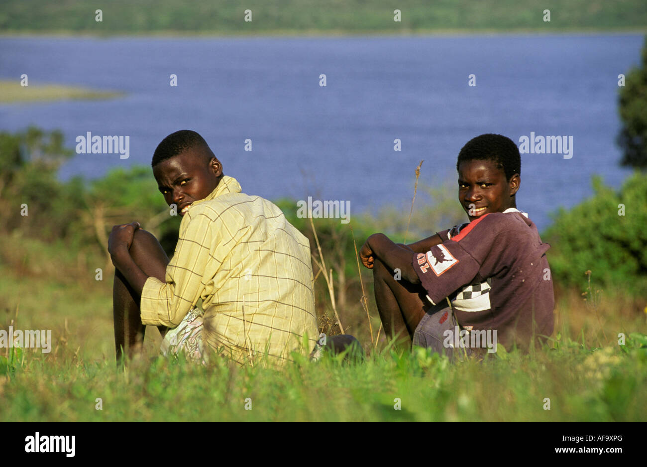 Due ragazzi Zulu seduta vicino alla riva del lago Mgobezeleni Baia di Sodwana potete, northern Kwazulu Natal; Sud Africa Foto Stock