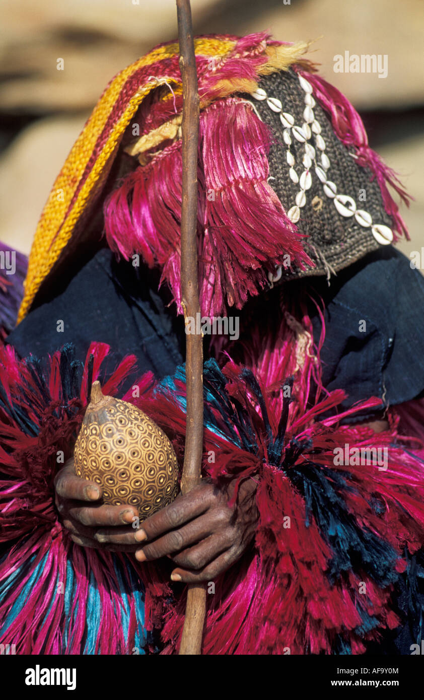 Ritratto di ballerina Dogon che mostra sonaglino e stick vicino a Bandiagara scarpata, Paese Dogon del Mali Foto Stock