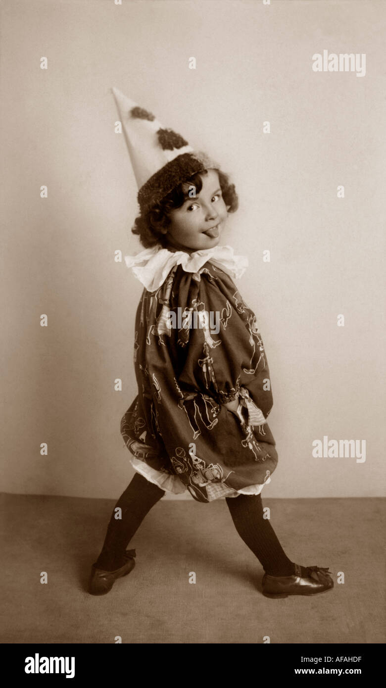 Bambino vestito in costume da clown nel periodo edoardiano prendendo il suo o la sua linguetta Foto Stock